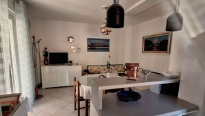Una cucina moderna con mobili bianchi, un'isola centrale e luci a sospensione.