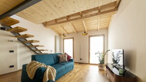 A modern living room with a blue sofa, wooden flooring, a TV stand, and a staircase. - Industrial design loft with outdoor living terrace (Florence)