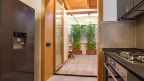 A kitchen with a stove, a refrigerator, and a wooden ceiling. - Industrial design loft with outdoor living terrace (Florence)