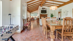 A spacious kitchen with wooden beams, a dining area with wooden chairs, and a foosball table. - Ask for 20% Off, Cozy Home, Riverfront, Nature (New Braunfels)