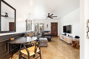 A modern living room with a dining area, a TV, and a ceiling fan.