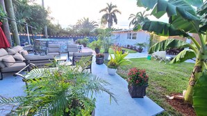An outdoor patio area with a pool, seating, and various potted plants.