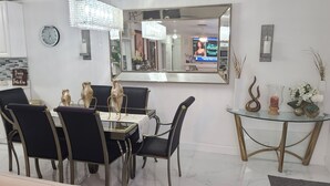 A dining area with a round table, black chairs, a chandelier, a mirror, and decorative items.