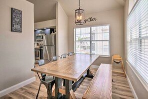 A modern kitchen with a dining area, featuring a wooden table, chairs, and a bench. - Cozy + Deluxe Branson Condo w/ Covered Balcony (Branson)