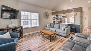 A spacious living room with a large flat-screen TV, a wooden coffee table, and a gray sofa. - Cozy + Deluxe Branson Condo w/ Covered Balcony (Branson)