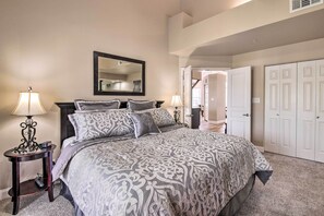 A bedroom with a large bed, two bedside tables with lamps, a mirror above the bed, and a closet with three doors. - Cozy + Deluxe Branson Condo w/ Covered Balcony (Branson)