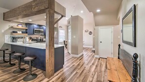 A modern kitchen with a central island, bar stools, and a wooden bench. - Cozy + Deluxe Branson Condo w/ Covered Balcony (Branson)