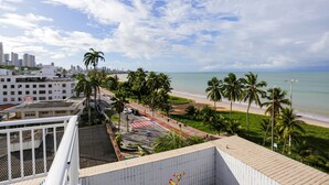 A coastal cityscape with a beach, palm trees, and a view of the ocean. - Carpediem - Apart beira mar Cabo Branco (João Pessoa)