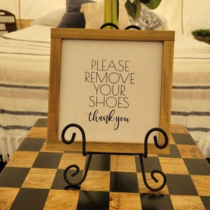 Un letrero en marco con el texto “Por favor, quítese los zapatos, gracias” sobre una mesa a cuadros.