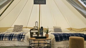 A tent with a bed, pillows, a small table with a sign, and a welcome sign. - Lovers Lookout 3 at Big Rock Creek (Saint Croix Falls)