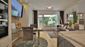 Ein modernes Hotelzimmer mit einem Bett, einer Couch, einem Esstisch und einem Fernseher.
