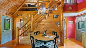 Interior de madera con zona de comedor, escalera y pared roja de acento.