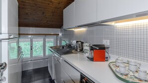 A kitchen with white cabinets, a stainless steel sink, a coffee maker, and a tray with cups. - Spazioso appartamento centralissimo con wi-fi. (Cortina d´Ampezzo)