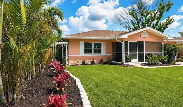 A single-story house with a well-maintained lawn and a variety of plants.