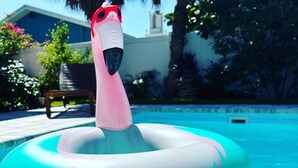 Une piscine avec un flotteur gonflable rose et une personne allongée dessus.