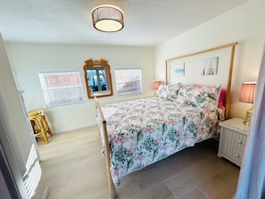 A bedroom with a bed, two bedside lamps, a nightstand, a mirror, and a window with blinds. -  FALL DISCOUNT! Tropical Beach Bungalow w/Private Saltwater Pool and Pool House (St. Pete Beach)