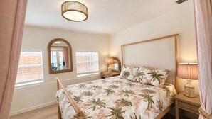 Une chambre à coucher avec un lit, un miroir, deux lampes de chevet et une fenêtre avec des stores.