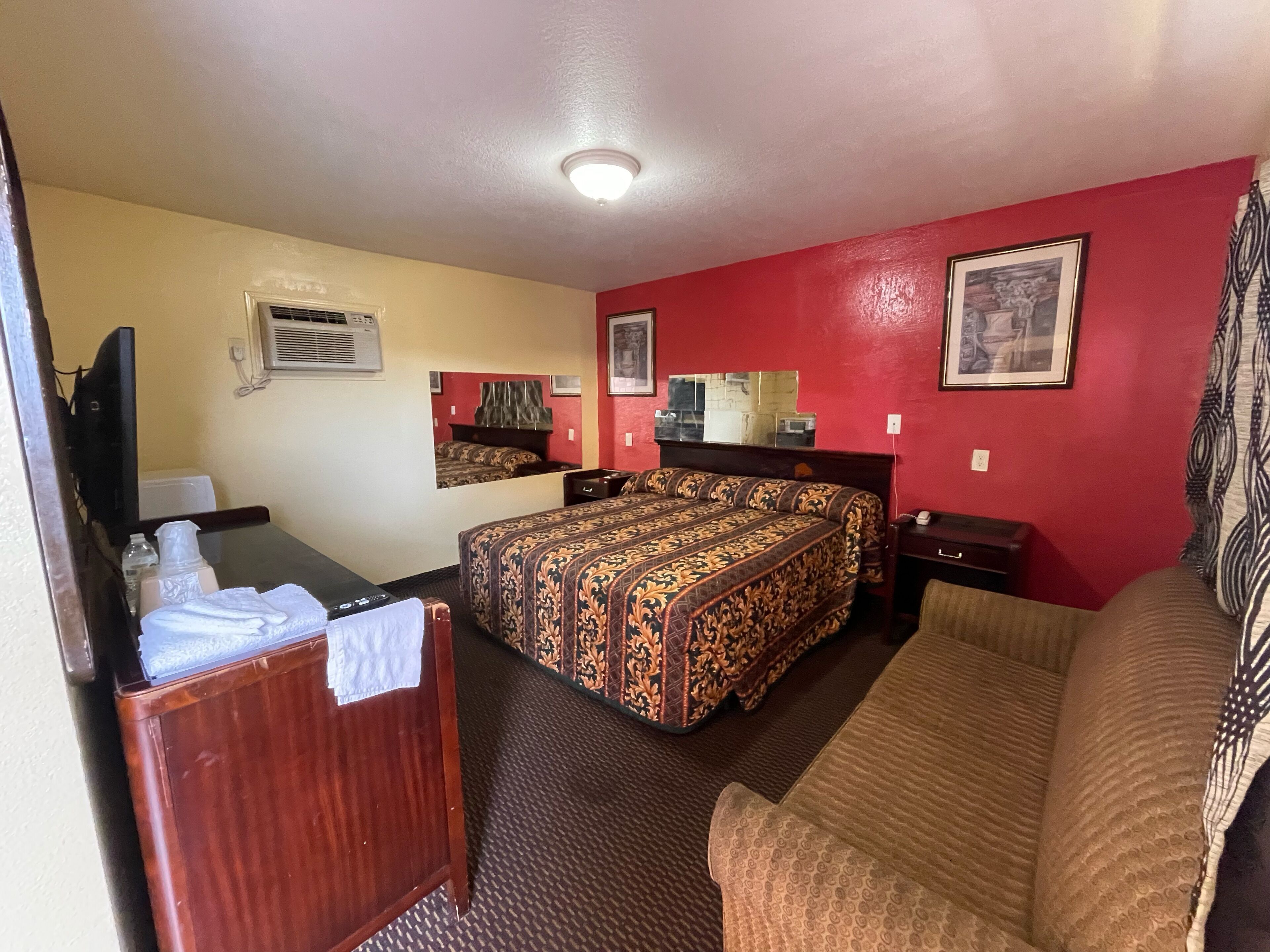 A hotel room with a bed, a sofa, a desk, and a TV.