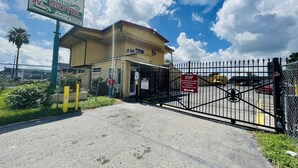 A gated entrance to a motel with a sign indicating it offers RV parking, a daily & weekly rate, and a kitchen. - Royal Palms Motel & RV Park (New Orleans)
