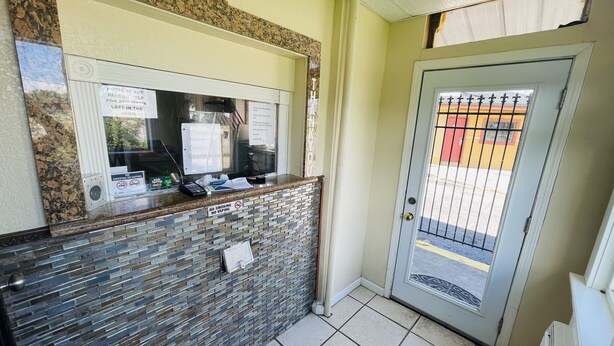 A hotel reception area with a stone counter, a glass door, and a view of the parking lot. - Royal Palms Motel & RV Park (New Orleans)