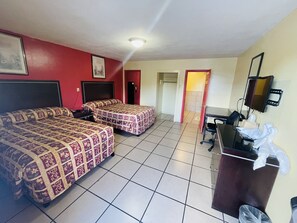 A hotel room with two beds, a desk, a chair, a television, and a trash bin. - Royal Palms Motel & RV Park (New Orleans)