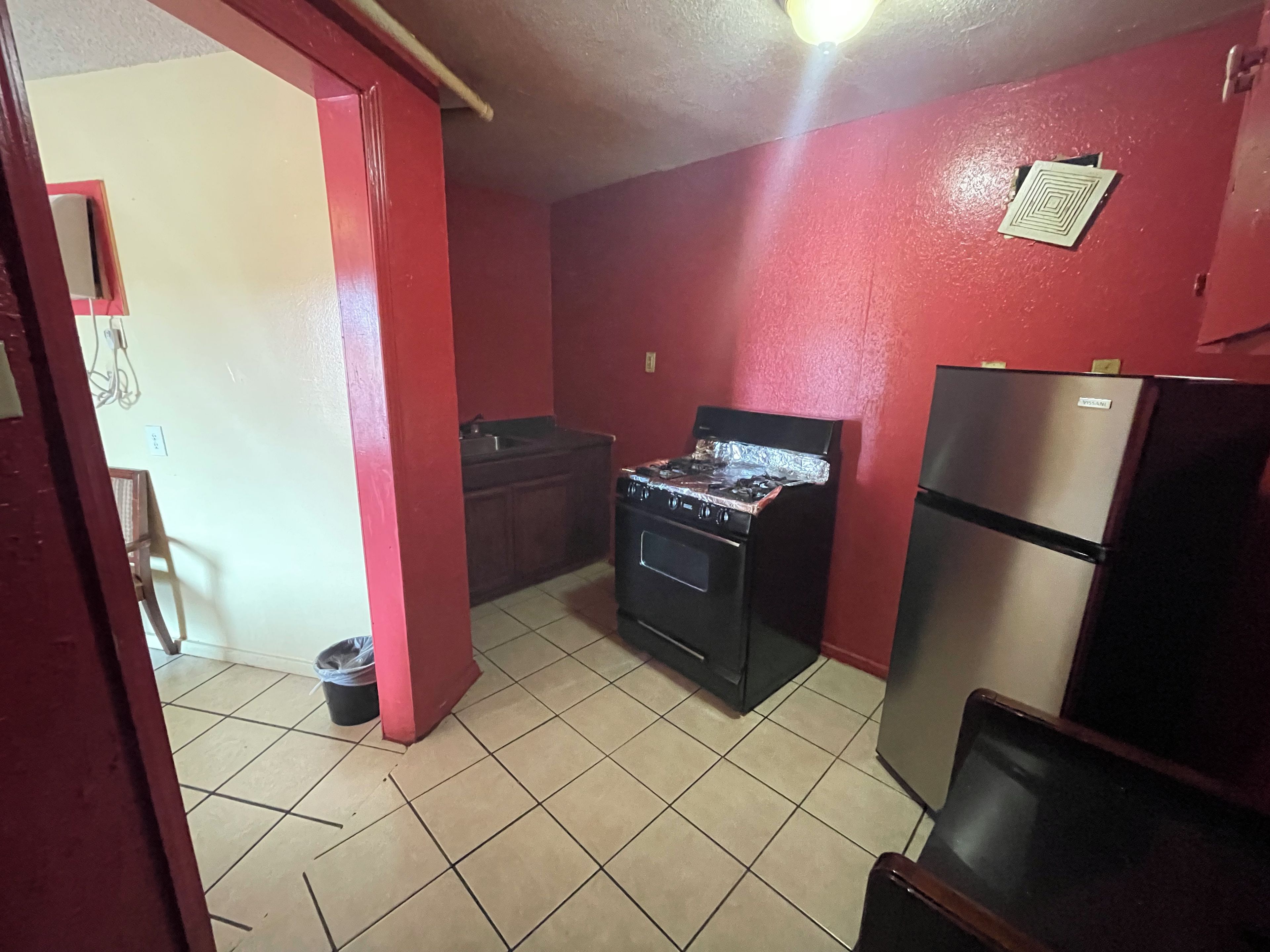 A compact kitchen with a gas stove, a refrigerator, and a sink.