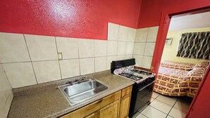 A kitchen with a sink, stove, and wooden cabinets. - Royal Palms Motel & RV Park (New Orleans)