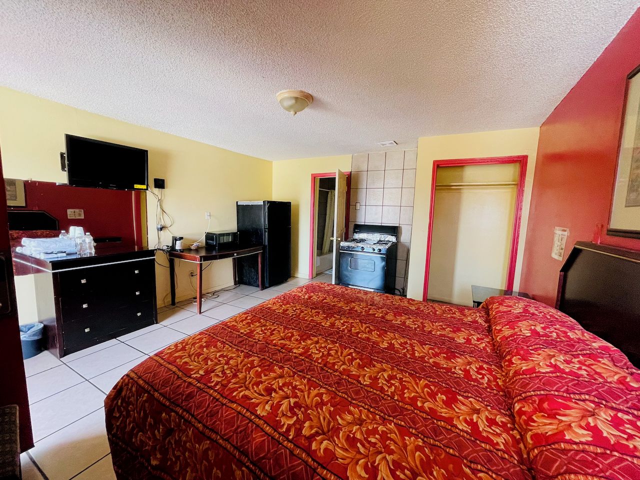 A hotel room with a bed, a desk, a refrigerator, and a stove.