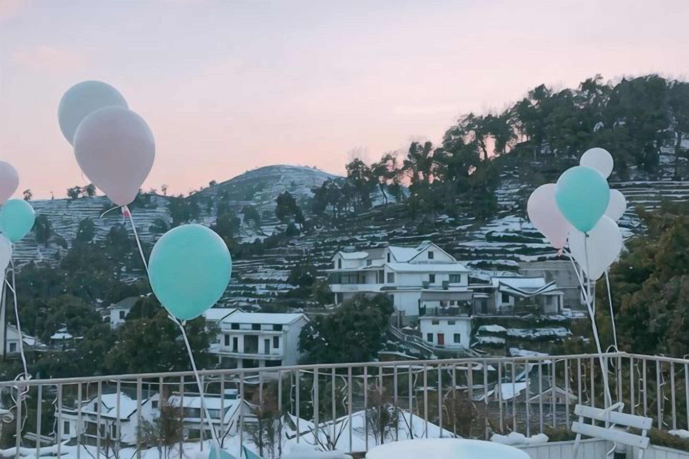 A view of a snow-covered landscape with houses and balloons.