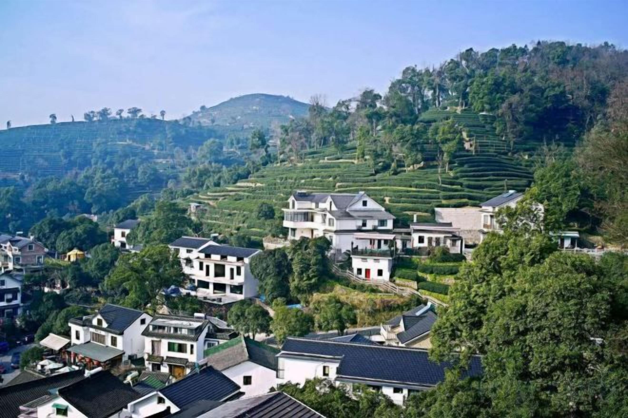 Un pueblo en la ladera de una colina con arquitectura tradicional, campos en terrazas y un cielo despejado.