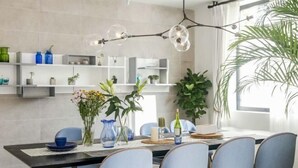 Ein moderner Essbereich mit einem schwarzen Tisch, blauen Stühlen und einer Chandelüster.