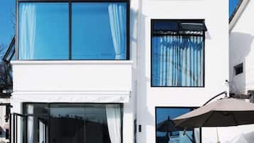 Un edificio moderno con grandes ventanales, una entrada de vidrio y un espacio exterior visible con una sombrilla.