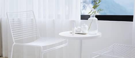 A white metal chair and table with toiletries, a window with a mountain view, and a white radiator.