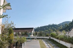 Pátio com deck de madeira, plantas em vasos e uma escultura de metal.