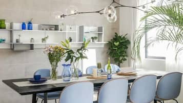 A dining area with a black table, blue chairs, and a hanging light fixture.