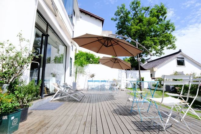 Une terrasse extérieure avec une plateforme en bois, un grand parasol et du mobilier d’extérieur.