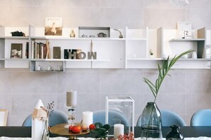 A modern kitchen with white cabinetry, a dining table with blue chairs, and a decorative vase on the table. - Hangzhou Liubai Homestay (Hangzhou)