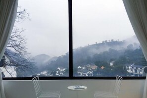 Une pièce avec une grande fenêtre, deux chaises et une petite table.