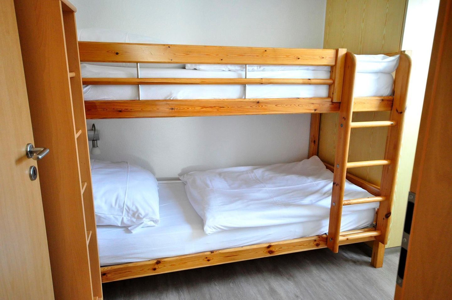 A bunk bed with two levels, each with white bedding.