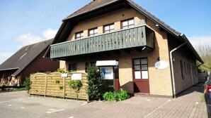 Een gebouw met twee verdiepingen, een balkon, bakstenen muren en een schuin dak.