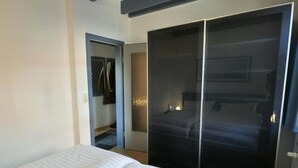 Een slaapkamer met een bed, een schuifdeurkast en een klein nachtkastje.