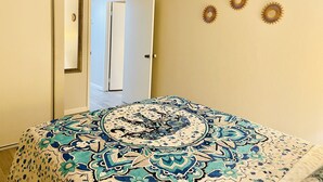 A bedroom with a bed, a door, and three wall decorations. - Two bedroom right off the strip (Las Vegas)