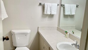A bathroom with a toilet, sink, and mirror. - Two bedroom right off the strip (Las Vegas)