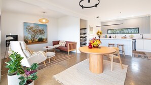 Una sala de estar moderna con un sofá, una mesa de comedor y una zona de cocina con ventanal.