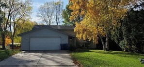 A single-story house with a garage, surrounded by trees with autumn foliage. - All you need for your home away from home in MN (Sauk Rapids)