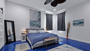 A bedroom with a bed, bedside tables, a mirror, and artwork on the walls.