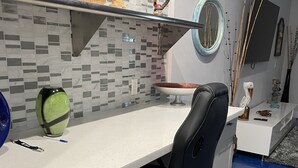 A modern office space with a white desk, black office chair, and a patterned rug.