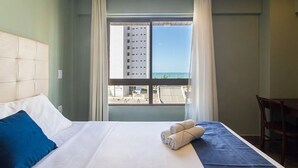 Una habitación de hotel con una cama, vistas al mar y un balcón.