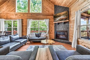 Un interior de cabaña acogedor con chimenea, paredes de madera y un sofá.