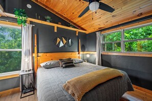 Une chambre à coucher avec un lit, un ventilateur de plafond, une fenêtre et une plante.